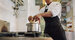 Chef adding food ingredients in stainless steel pot on stove. Cropped shot of male cook preparing food in restaurant kitchen.